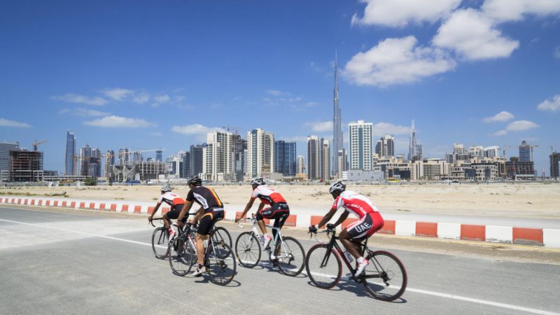 Cyclists on cycle track with skyline of Dubai, United Arab Emirates.